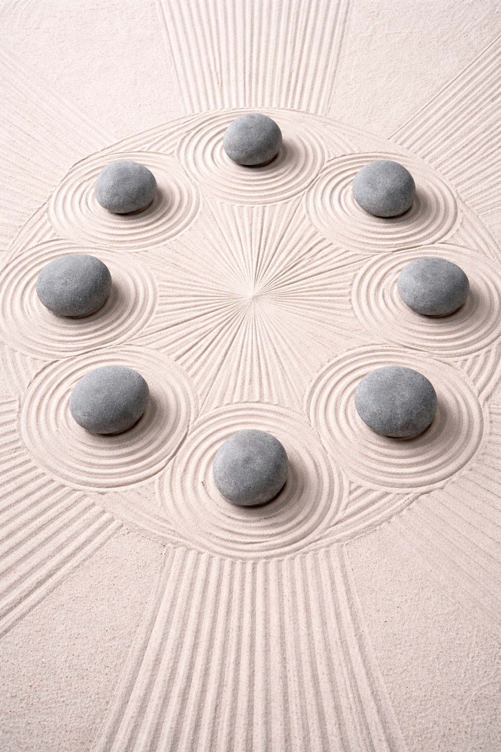Smooth grey stones arranged in a circle on raked sand